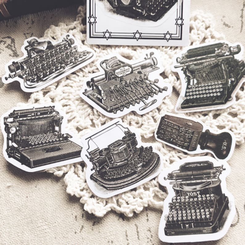 May include: A collection of vintage typewriter stickers in black and white. The stickers feature different styles of typewriters, including a manual typewriter, an electric typewriter, and a portable typewriter. The stickers are perfect for adding a vintage touch to your journals, planners, or scrapbooks.