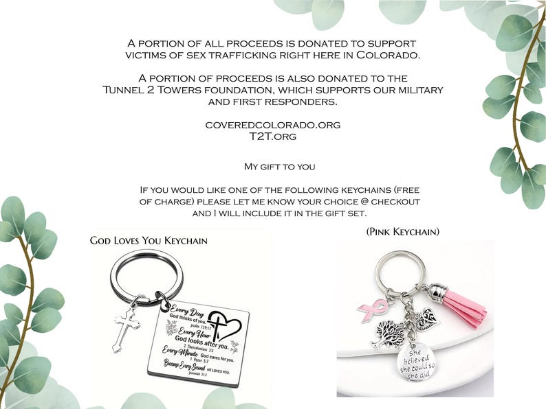 May include: Two metal keychains: one rectangular silver-toned tag with a cross charm and religious text, and one silver-toned ring with a pink tassel, a pink ribbon charm, a tree charm, a heart charm, and a round tag reading She believed she could so she did.