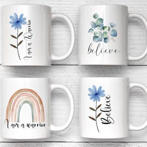 Op de afbeelding: Vier witte keramische mokken gerangschikt in een raster. Mok 1 heeft een blauwe bloem en de tekst 'I am a Warrior'. Mok 2 toont groene eucalyptusbladeren en het woord 'believe'. Mok 3 toont een gedempte regenboog en 'I am a warrior'. Mok 4 heeft een blauwe bloem en 'Believe'.