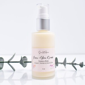 May include: A clear glass bottle with a silver pump top filled with a white lotion. The bottle label is pink and says "Scarlet Acne Renew + Glow Serum Vanilla Rose Vitamin C, Peptides & Niacinamide 2 oz".