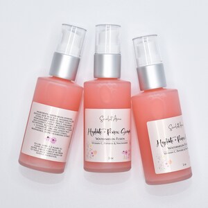 Op de afbeelding: Drie flessen van 2 oz met roze vloeistof en een witte pomp. De flessen zijn gelabeld met "Hydrate + Renew Serum Watermeloen Fusion Vitamine C, Peptiden & Niacinamide".
