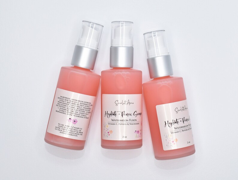 Op de afbeelding: Drie flessen van 2 oz met roze vloeistof en een witte pomp. De flessen zijn gelabeld met "Hydrate + Renew Serum Watermeloen Fusion Vitamine C, Peptiden & Niacinamide".