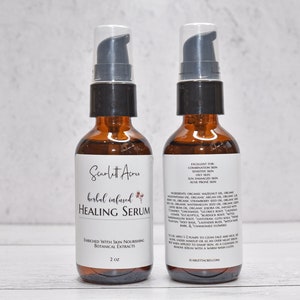 May include: Two amber glass bottles with black pump tops and white labels. The front label reads "Scarlett Acres herbal infused HEALING SERUM" with a small floral design. The back label lists ingredients and instructions for use. The bottles are 2 oz each.