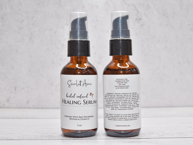 May include: Two amber glass bottles with black pump tops and white labels. The front label reads "Scarlett Acres herbal infused HEALING SERUM" with a small floral design. The back label lists ingredients and instructions for use. The bottles are 2 oz each.