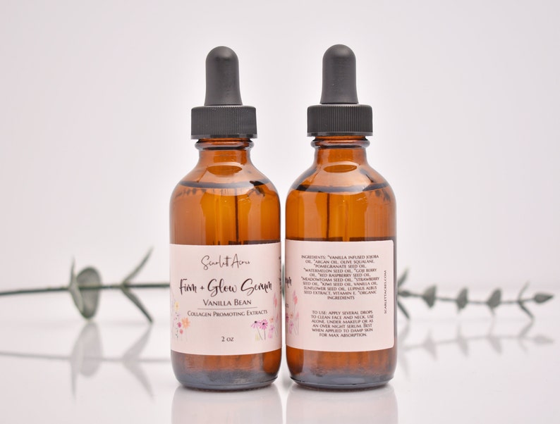 Puede incluir: Dos botellas de vidrio &aacute;mbar con goteros negros llenas de un l&iacute;quido transparente. Las botellas est&aacute;n etiquetadas con "Firm + Glow Serum" y "Vanilla Bean Collagen Promoting Extract". Las botellas est&aacute;n sobre una superficie blanca con un tallo de planta verde en el fondo.
