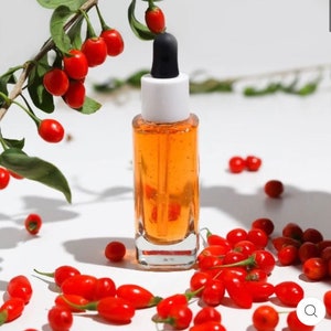 May include: A glass bottle of orange liquid with a dropper top. The bottle is surrounded by red goji berries.