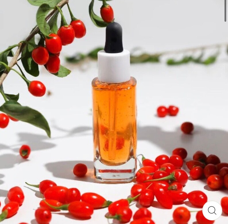 May include: A glass bottle of orange liquid with a dropper top. The bottle is surrounded by red goji berries.