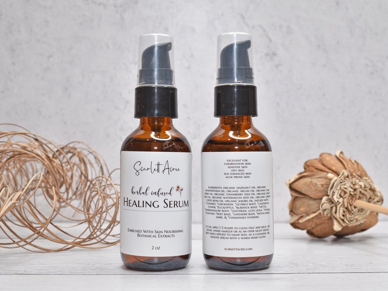 May include: Two amber glass bottles with black pump tops filled with a herbal infused healing serum. The bottles are labeled "Scarlett Acru" and "herbal infused HEALING SERUM". The bottle on the right has a list of ingredients and instructions for use.
