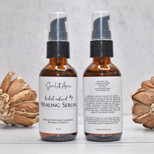 May include: Two amber glass bottles with black pump tops filled with a clear liquid. The bottles are labeled "Scarlett Acru Herbal Infused Healing Serum" and list ingredients and instructions for use. The bottles are sitting on a white surface with dried flowers on either side.