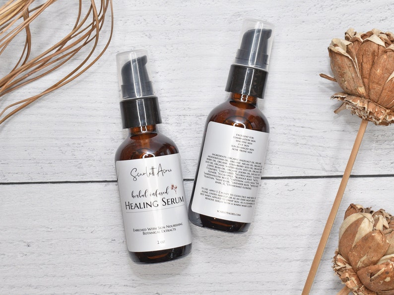 May include: Two amber glass bottles with black pump tops filled with a clear liquid. The bottles are labeled "Scarlet Acres Herbal Infused Healing Serum" and contain 2 fl oz. The bottles are on a white wooden surface.