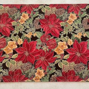 May include: A black fabric table runner with a red and gold floral pattern featuring poinsettias, roses, and pine cones.