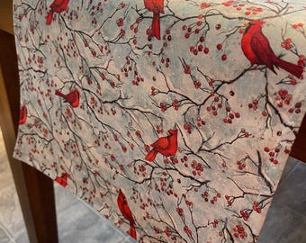 Cardinals and berries on snowy soft blue table runners, sold in several sizes.