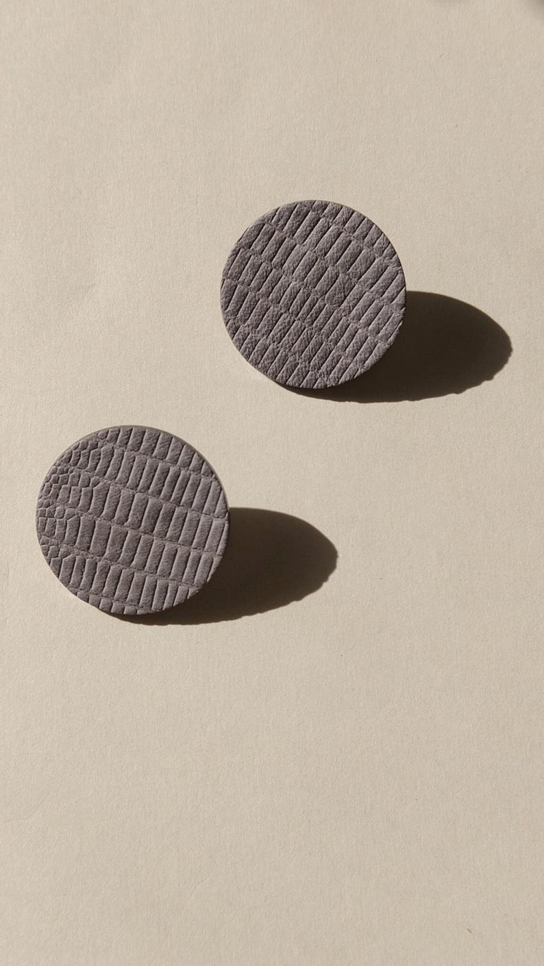 Make a bold statement with these oversized grey raptile embossed leather stud earrings, designed for lovers of minimalist style with a modern urban edge. Crafted from exceptionally soft genuine leather, these large yet ultra-lightweight earrings offer striking presence without compromising comfort.