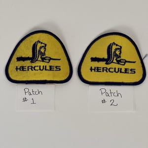 May include: Two yellow and navy blue Hercules patches. Each patch has a navy blue border and features a stylized image of Hercules with the word "HERCULES" in black text below the image. Each patch has a white label with the text "Patch #1" and "Patch #2".