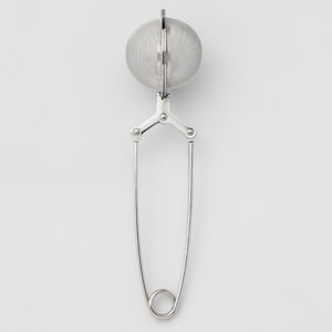 May include: A silver tea infuser with a round mesh ball and a long handle. The handle is made of two pieces of metal that are connected by a hinge.
