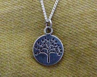 May include: A silver chain necklace with a silver pendant featuring a tree design. The pendant is round and has a detailed tree with branches and leaves.