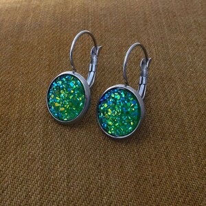 May include: A pair of silver hoop earrings with green glitter round cabochon stones.