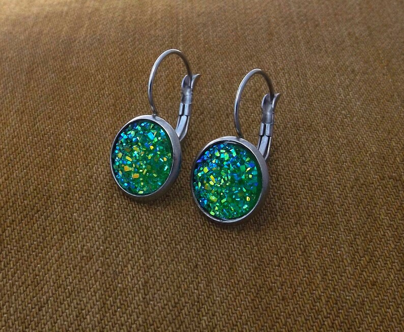 May include: A pair of silver hoop earrings with green glitter round cabochon stones.