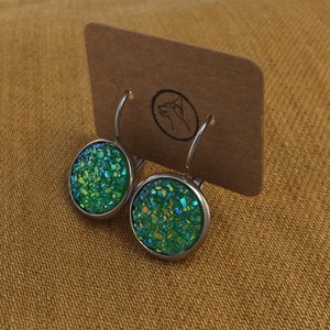 May include: A pair of silver hoop earrings with green glitter round cabochon stones.