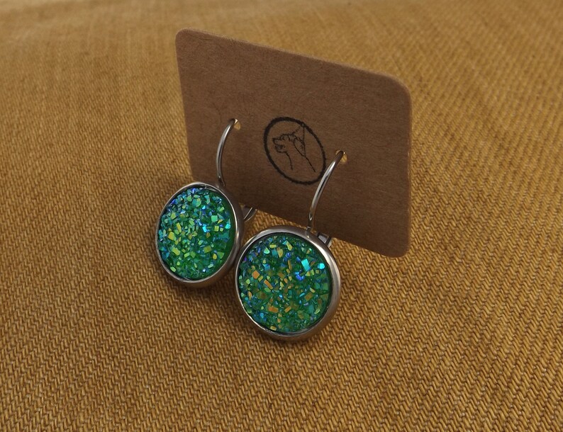 May include: A pair of silver hoop earrings with green glitter round cabochon stones.