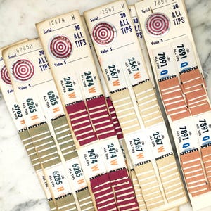 May include: A close-up of several vintage ticket stubs with a red and white target design. The tickets are labeled with serial numbers and the text "30 ALL TIPS".