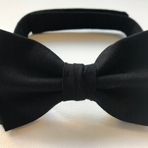 Puede incluir: Una pajarita negra con nudo preatado y banda ajustable para el cuello. La pajarita est&aacute; hecha de tela negra lisa y est&aacute; dise&ntilde;ada para eventos formales u ocasiones especiales. La banda del cuello tiene un cierre de velcro.