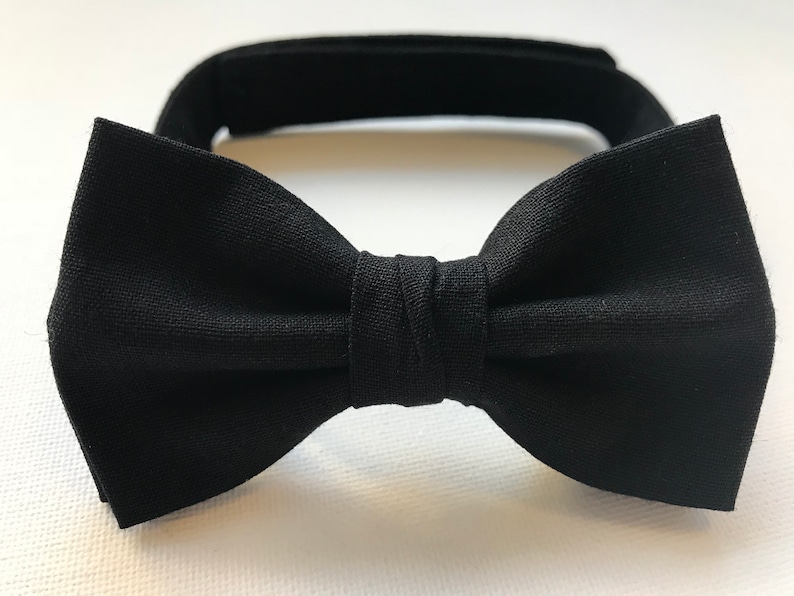 Puede incluir: Una pajarita negra con nudo preatado y banda ajustable para el cuello. La pajarita est&aacute; hecha de tela negra lisa y est&aacute; dise&ntilde;ada para eventos formales u ocasiones especiales. La banda del cuello tiene un cierre de velcro.