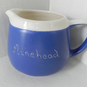 May include: A blue ceramic pitcher with a white rim and the word "Minehead" inscribed on the side.