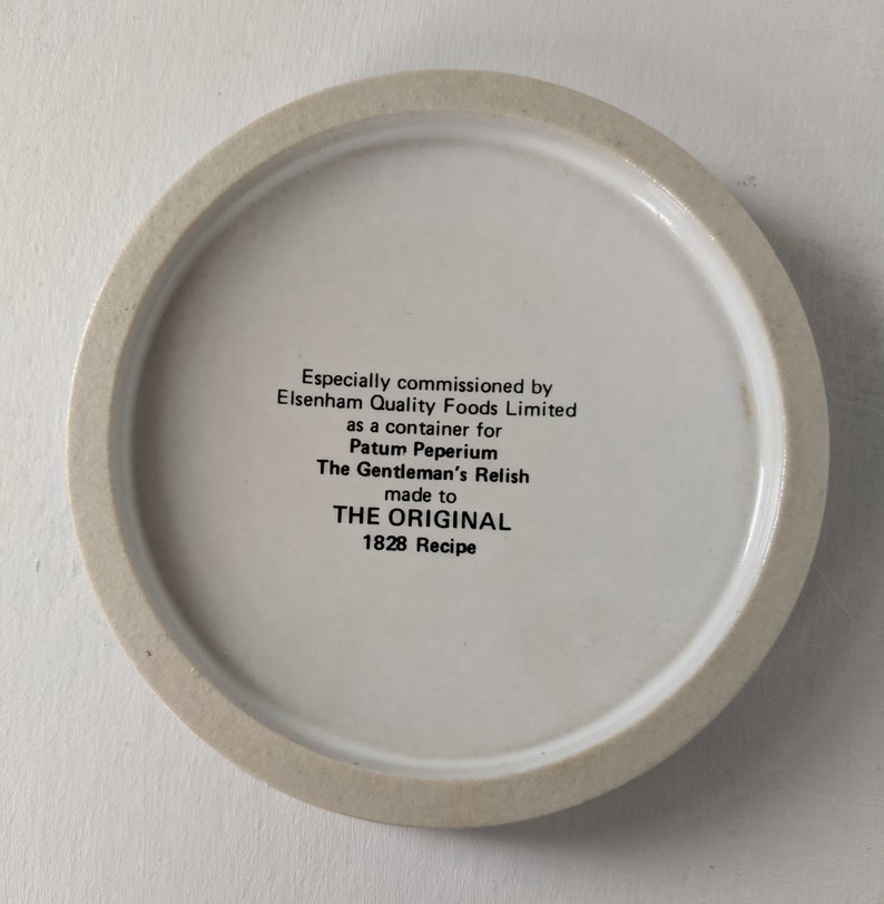Może przedstawiać: Biała ceramiczna pokrywka do słoika z czarnym tekstem, kt&oacute;ry brzmi: "Especially commissioned by Elsenham Quality Foods Limited as a container for Patum Peperium The Gentleman's Relish made to THE ORIGINAL 1828 Recipe"