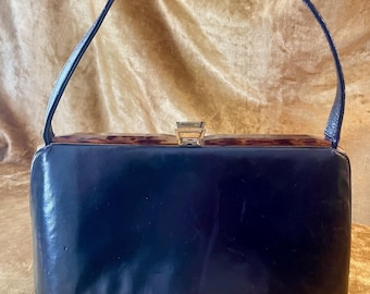 Vintage svart läderväska från 1950-talet med topphandtag, mockafoder och konstsköldpaddsmönster i Lucite-look