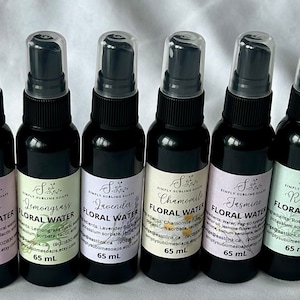 May include: Eight small black spray bottles with white labels. Each bottle contains a different floral water, including Eucalyptus, Rose, Lemongrass, Lavender, Chamomile, Jasmine, Rosemary, and Orange. The bottles are labelled with the name of the floral water and the size, 65 ml.
