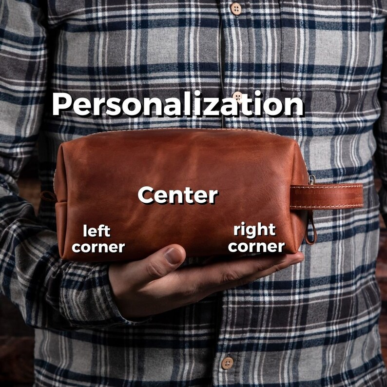 May include: A brown leather toiletry bag with a side handle and a zip closure. The bag features text overlays indicating personalisation options, including the words Personalisation, Center, left corner, and right corner, displayed on the surface.