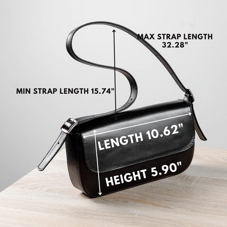 Op de afbeelding: Een zwarte schoudertas met klepsluiting en verstelbare riem. De tekst geeft een lengte van 26,97 cm, een hoogte van 14,99 cm en een riemlengte van minimaal 40 cm tot maximaal 82 cm aan.