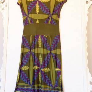May include: A green, purple, and blue patterned midi dress with a fitted bodice and a flowing skirt. The dress has a V-neckline and short sleeves.