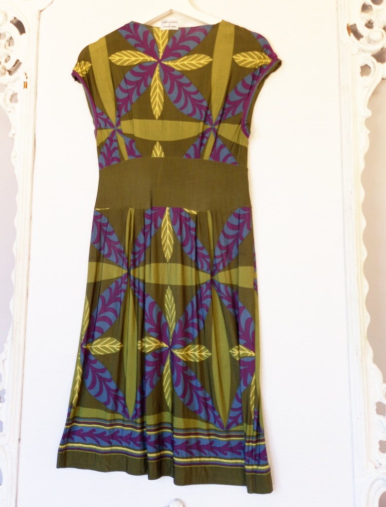 May include: A green, purple, and blue patterned midi dress with a fitted bodice and a flowing skirt. The dress has a V-neckline and short sleeves.