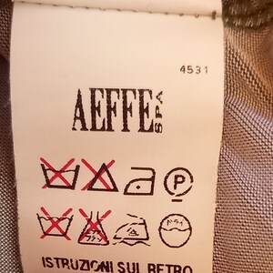 May include: A white clothing care label with red and black symbols. The label has the text "Aeffe" and the number "4531". The label also has the text "Istruzioni sul retro".