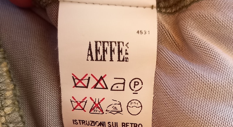 May include: A white clothing care label with red and black symbols. The label has the text "Aeffe" and the number "4531". The label also has the text "Istruzioni sul retro".