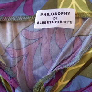 May include: A close-up of a green, purple, and blue patterned fabric with a white tag that reads "PHILOSOPHY DI ALBERTA FERRETTI".