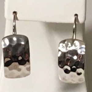 May include: A pair of silver hammered dangle earrings with a rectangular shape.