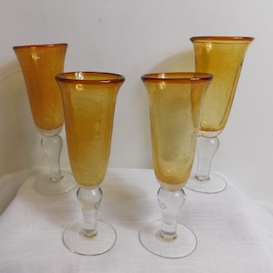 May include: A set of three ceramic mugs with a speckled, cream-colored glaze. Each mug features a different hand-painted floral design in shades of blue, green, and yellow. The mugs have a simple, rounded shape and a comfortable handle.