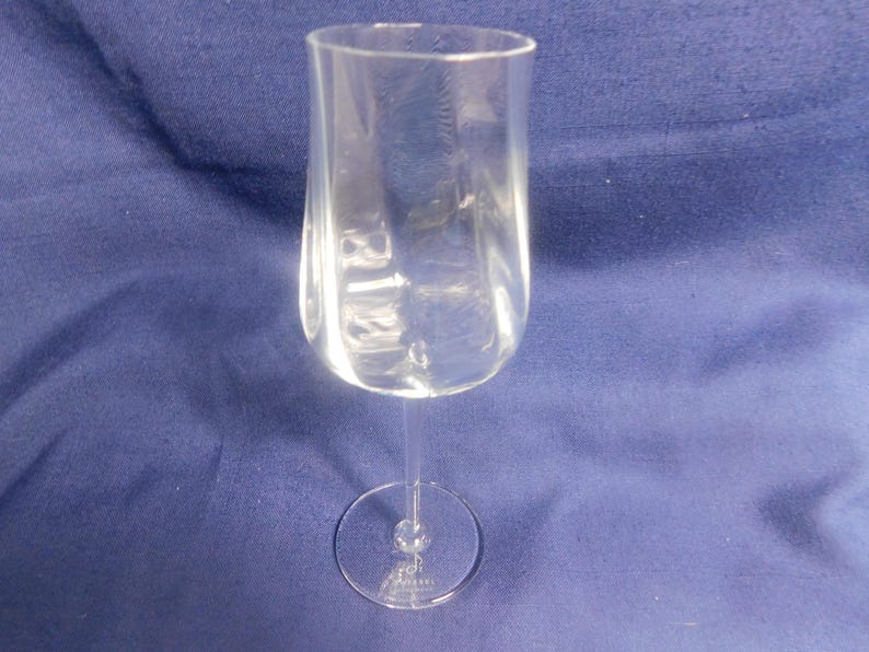 May include: A clear wine glass with a rounded bowl and a slender stem. The glass is made of transparent material. The base is a small, circular foot. The glass is designed for serving wine.
