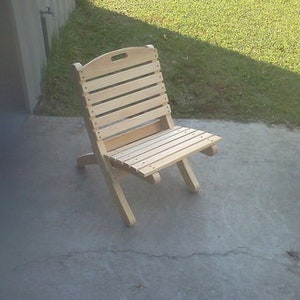 May include: A wooden folding chair with a natural finish. The chair has a slatted back and seat.