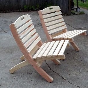 May include: Two wooden folding chairs with slatted backs and seats. The chairs are made of unfinished wood and have a natural color.