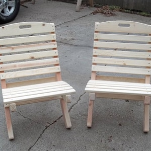 May include: Two wooden folding chairs with slatted backs and seats. The chairs are made of unfinished wood and are ready to be painted or stained.
