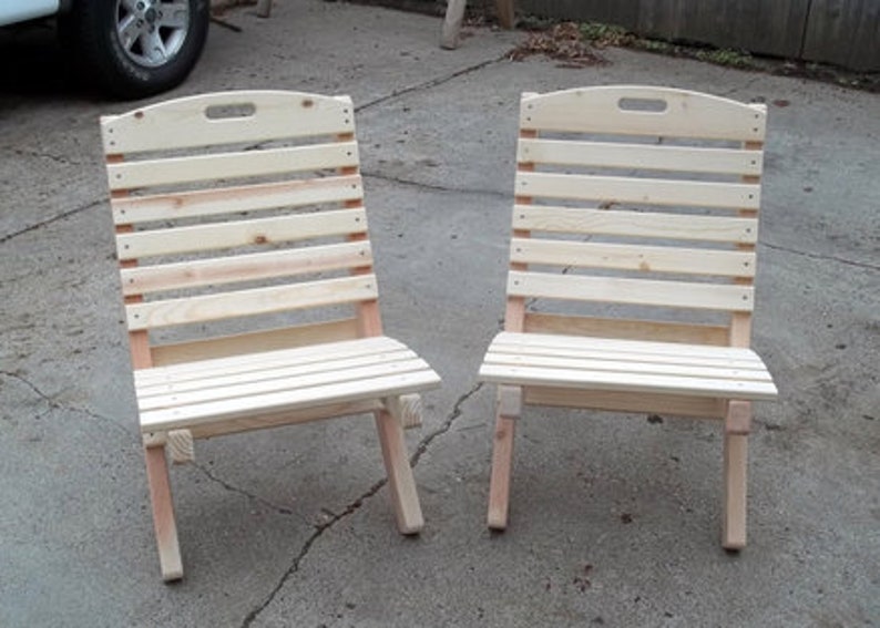 May include: Two wooden folding chairs with slatted backs and seats. The chairs are made of unfinished wood and are ready to be painted or stained.