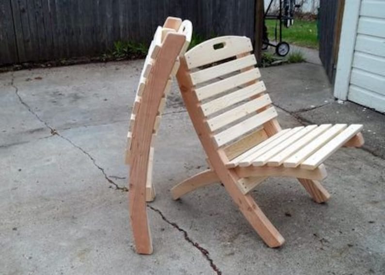 May include: Two wooden folding chairs with slatted backs and seats. The chairs are made of natural wood and are in a folded position.