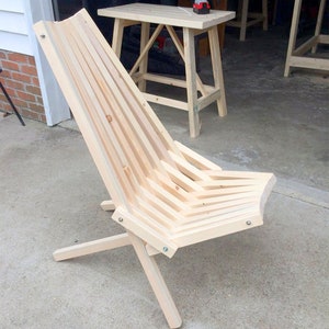 May include: A wooden folding chair with a slatted back and seat. The chair is made of unfinished wood and has a simple, modern design.