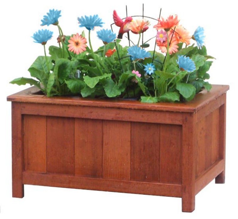 May include: A wooden planter box with a dark brown stain. The planter is filled with green plants and colorful flowers, including blue, pink, and orange.