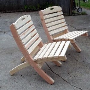 K&ouml;nnte beinhalten: Zwei Klappst&uuml;hle aus Holz mit Lattenr&uuml;cken und -sitzen. Die St&uuml;hle sind aus unbehandeltem Holz und haben eine nat&uuml;rliche Farbe.