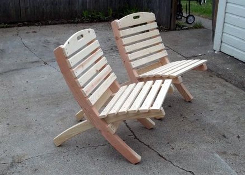 K&ouml;nnte beinhalten: Zwei Klappst&uuml;hle aus Holz mit Lattenr&uuml;cken und -sitzen. Die St&uuml;hle sind aus unbehandeltem Holz und haben eine nat&uuml;rliche Farbe.